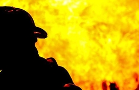 Firefighter in full protective gear in front of flames