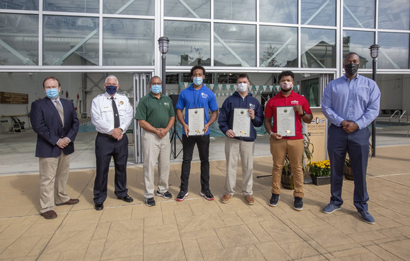 Image of county employees who saved man's life with Calvin Ball in front of Roger Carter Pool