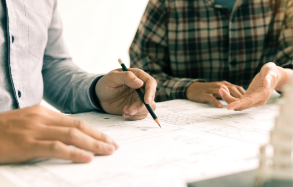 Image of two people meeting over blueprint documents