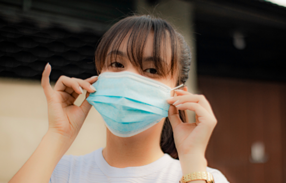 Image of woman with bangs putting on medical mask