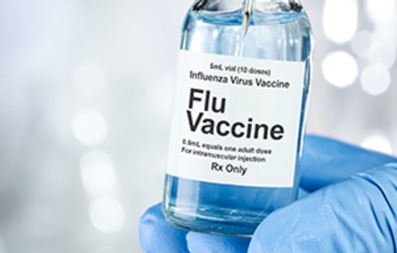 Gloved hand holding vial of flu vaccine