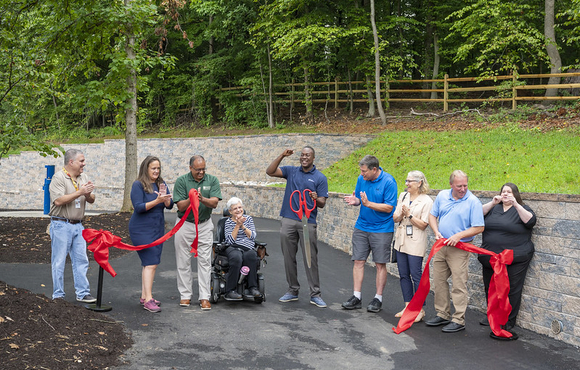 Image of officials holding a cut red ribbon on a wide pathway at Centennial Park