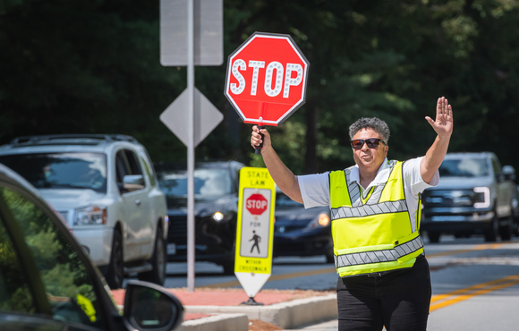 Crossing guard holds STOP sign in front of car