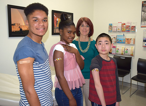 Three kids showing off band-aids after receiving vaccines from Health Officer Dr. Maura Rossman
