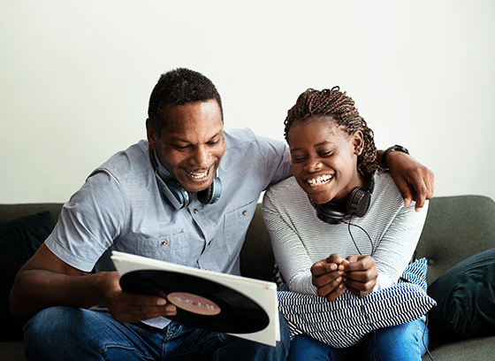 A father and daughter talking and smiling while looking at a vinyl record, enjoying music together.