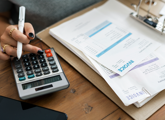 person looking over finance papers while using a calculator