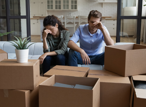 A couple surrounded by moving boxes. 