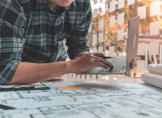 Engineer with laptop and plans on table