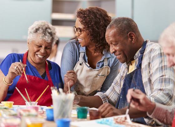 Group Of Retired Seniors Attending Art Class In Community Centre With Teacher 