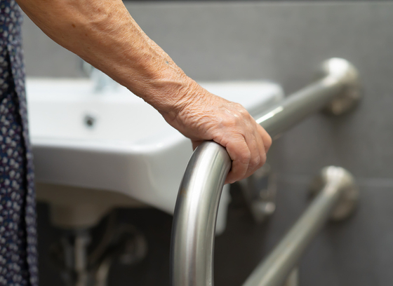 Older Adult uses toilet bathroom handle in the home 