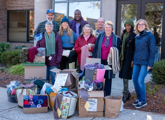 Photo of the the Tom Thumb Knitter's Club with County Executive Calvin Ball and OVMF manager Lisa Terry, surrounded by the scarves they knitted for deployed service members. is now underway,