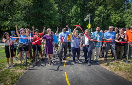 Calvin Ball joined by crowd cutting ribbon for bike path