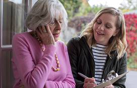 An older adult female talks with a door-to-door solicitor.