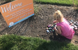 Image of young girl placing painted rocks in the dirt