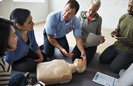 Four class participants listening to an instructor discuss CPR techniques