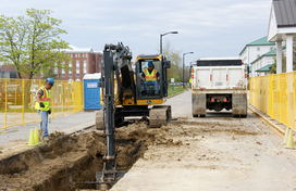Construction workers digging a hole in the street to access a water line