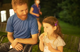 young girl eating smores with her dad