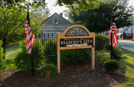 A welcome sign flanked by two American flags that reads, "Welcome to historic Ellicott City, established 1772."