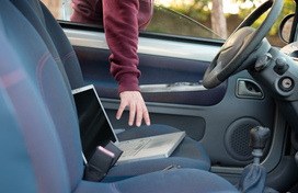 Person reaching for laptop in vehicle