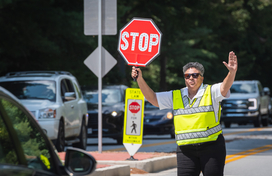Crossing guard holds STOP sign in front of car