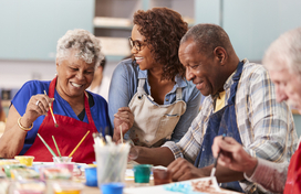 Group Of Retired Seniors Attending Art Class In Community Centre With Teacher 