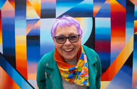 Older adult in front of art work 