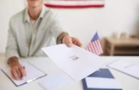 man hands over a paper with a vote sticker on it