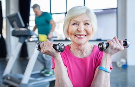 Older adult exercising with hand-held weights in a gym