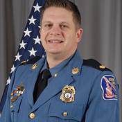 Major James Marshall standing in front of flag