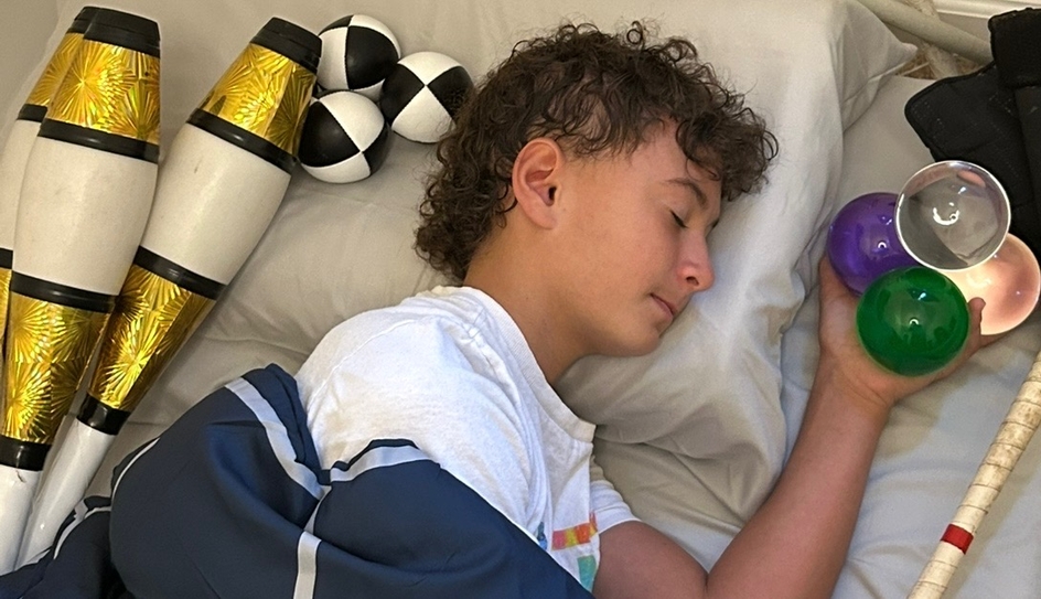 Young circus performer Adrian Caguin sleeps with his juggling objects