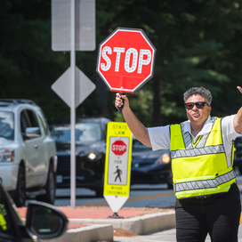 Crossing guard holds STOP sign in front of car